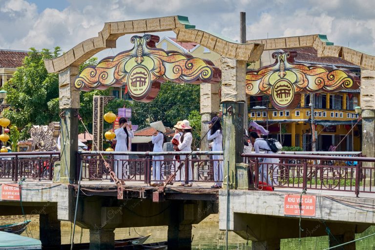 Vietnamese women wearing traditional Ao Dai on the Bridge of Lights (Cau An Hoi) in Hoi An, Vietnam