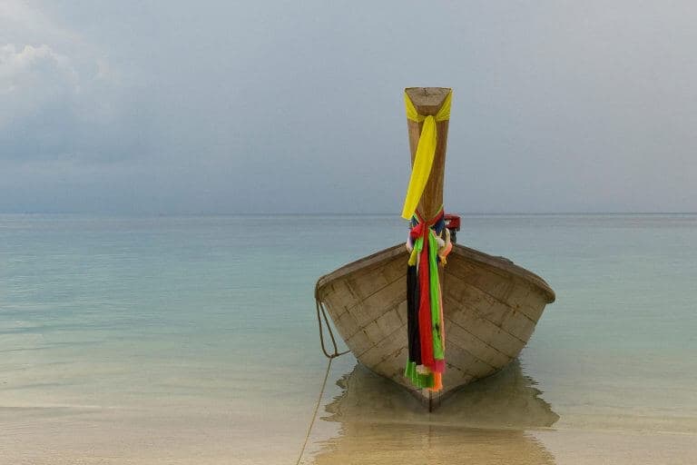A moored Longtail Boat with colourful pieces of silk cloth tied to the bowsprit at Phi Phi beach, Thailand