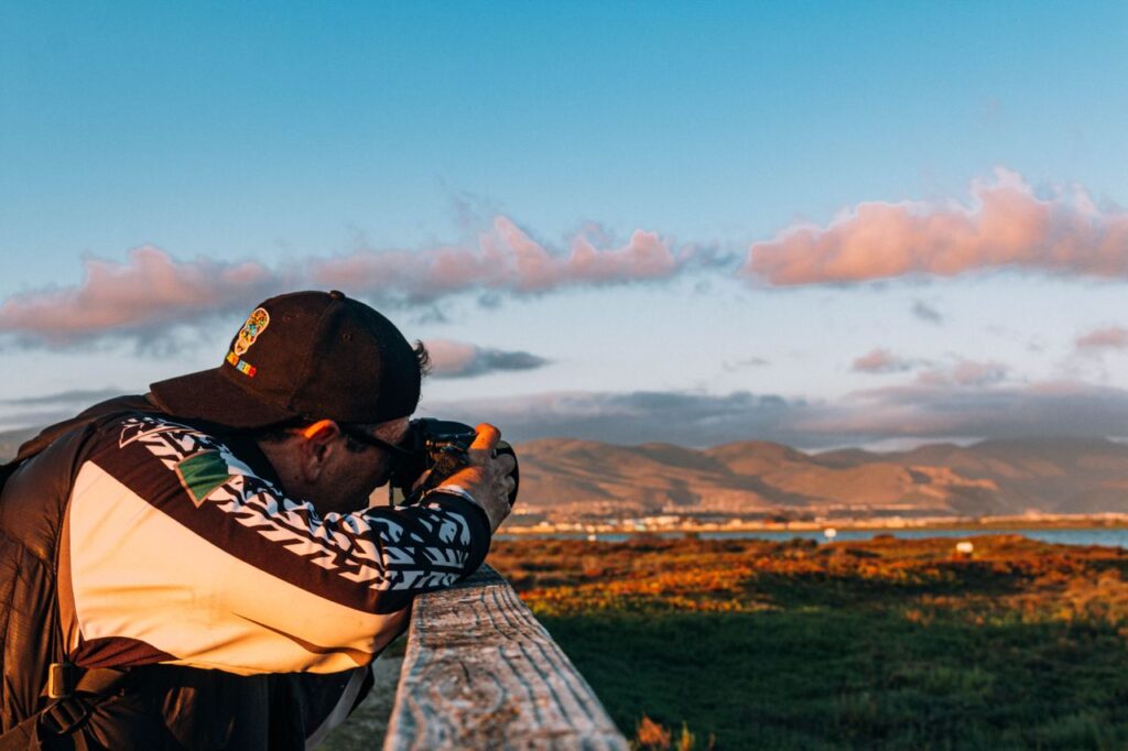 A man photographing a vast landscape during sunset, creating a vibrant and dynamic image.