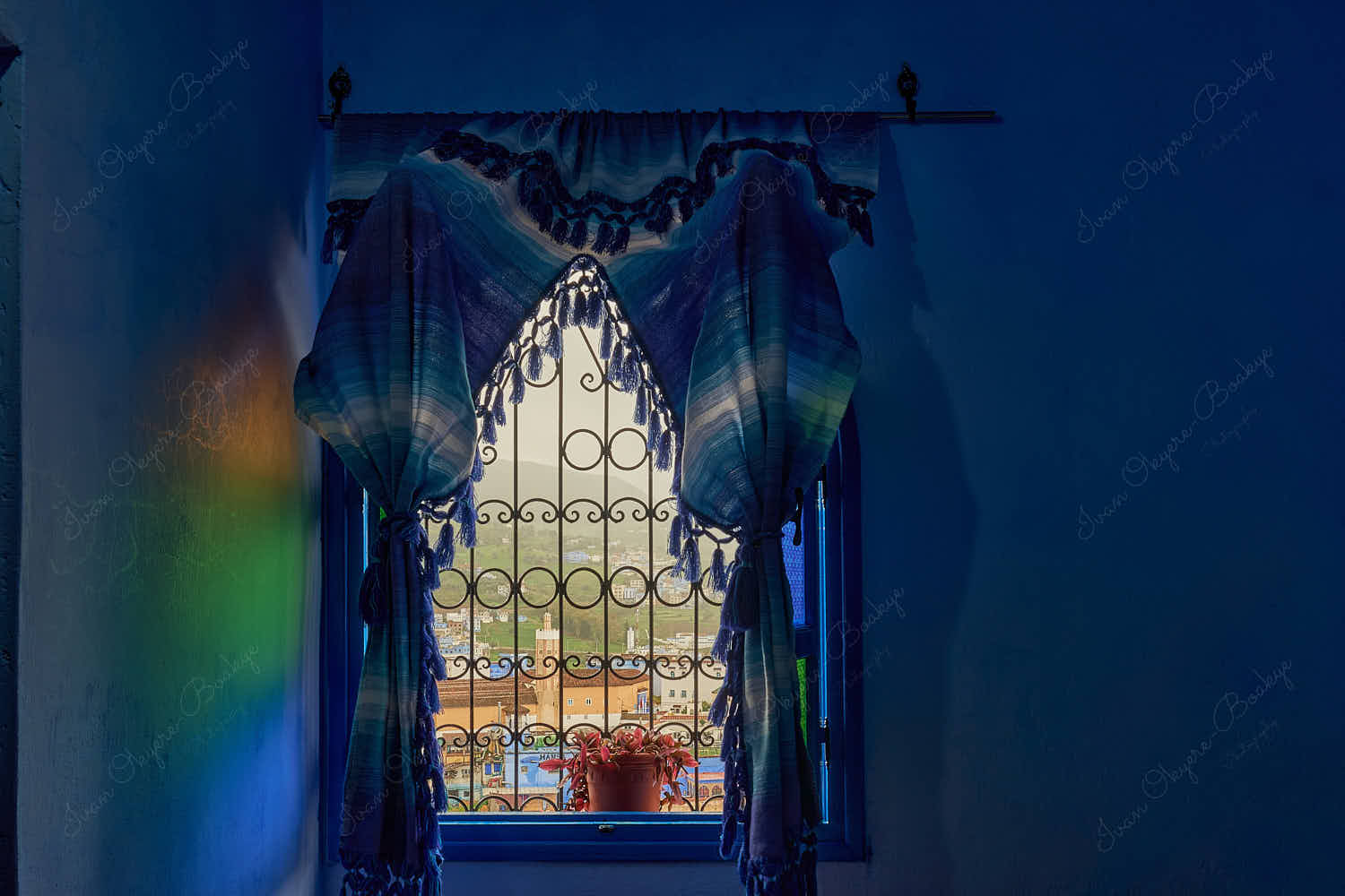 Diffused colors light through curtains framed open arched wooden window with a view of Grand Mosque of Chefchaouen and medina, Chefchaouen, Morocco