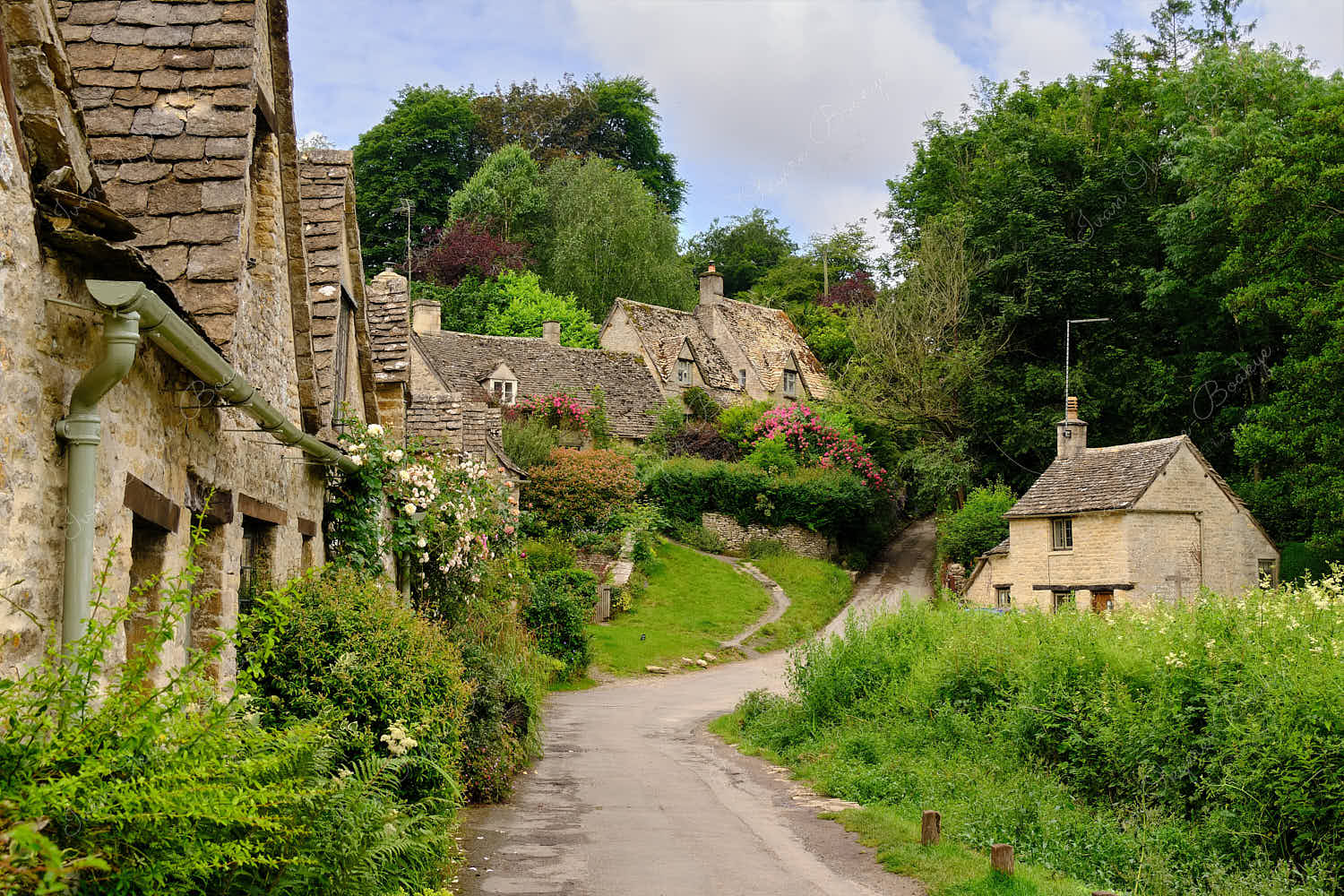 View from footpath leading past the famous picturesque Arlington Row Weavers Cottages, Bibury, Cotswolds, England, UK