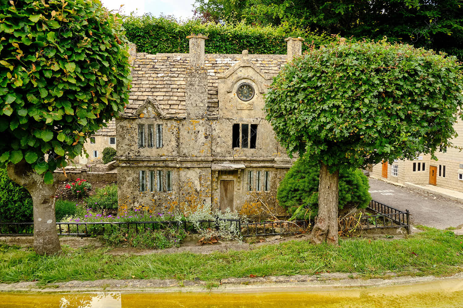 Elevated standing view of a miniature replica traditional English stone cottage and garden in Bourton on the Water Model Village, England, UK
