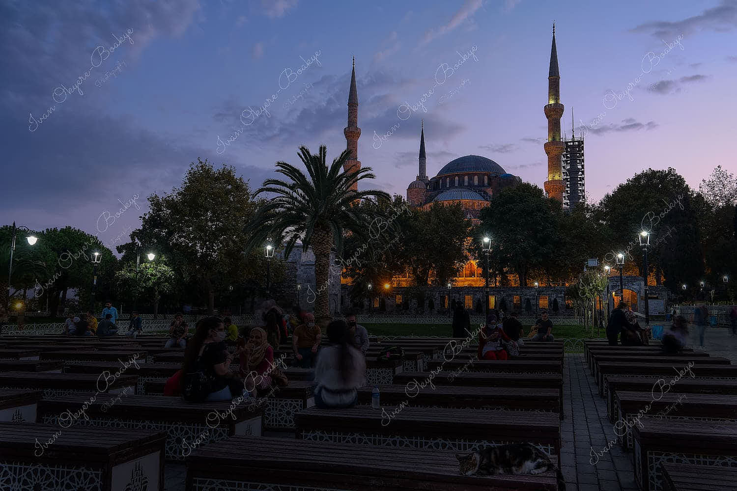 Local people sitting on benches outside the Blue Mosque at sunset, Istanbul, Turkey