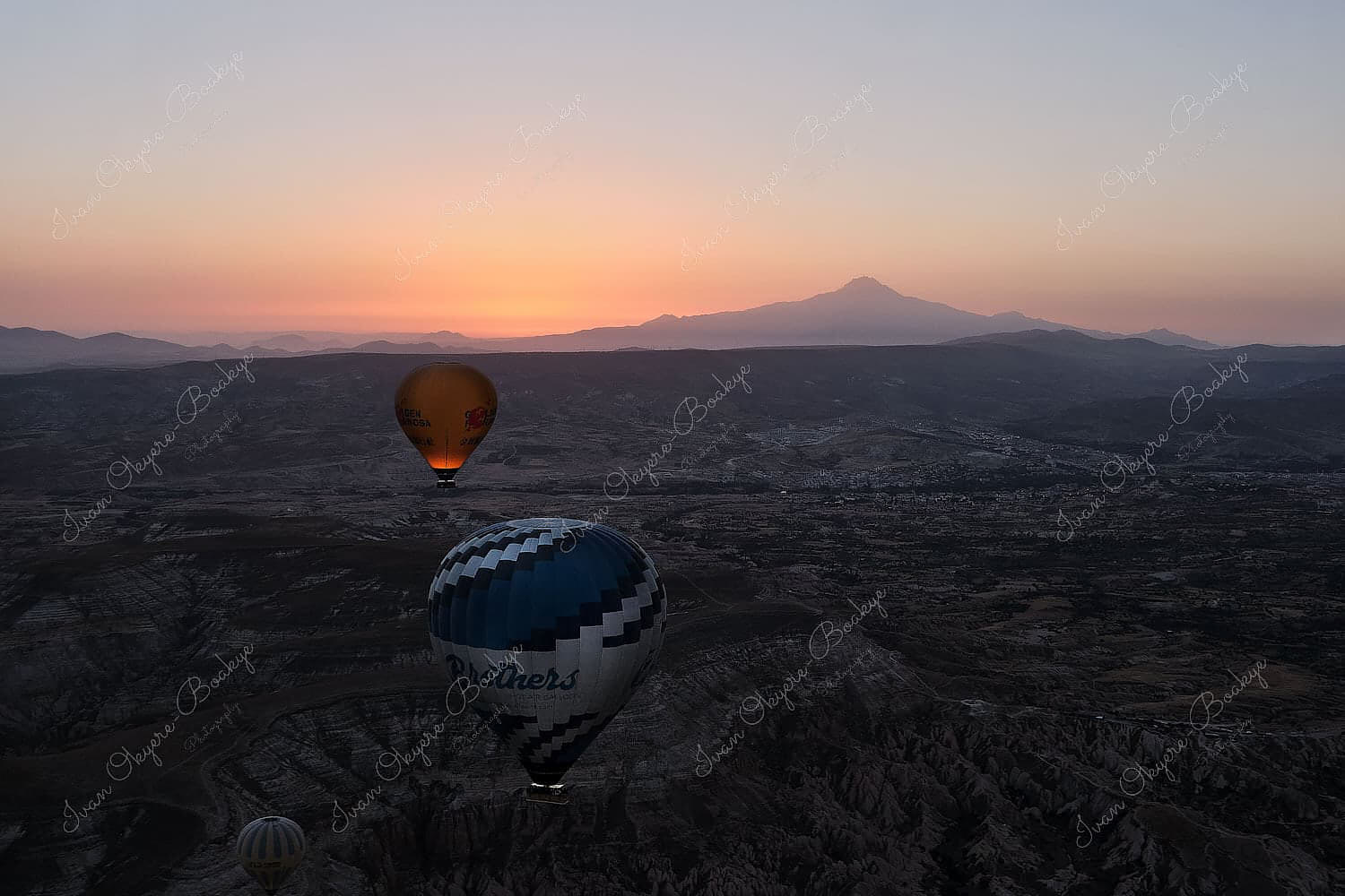 Hot air balloons floating at sunrise over the rock formations landscape of Cappadocia, Turkey