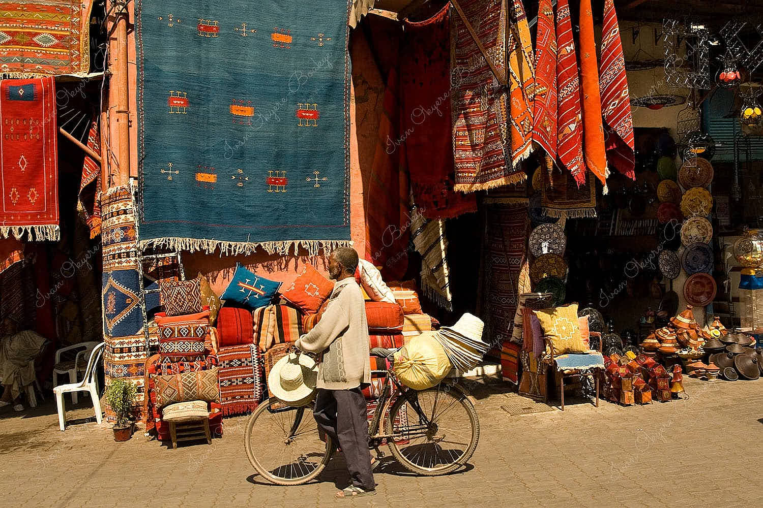 Man selling hats with his bicycle outside a carpet shop in a souq in Marrakech, Morocco