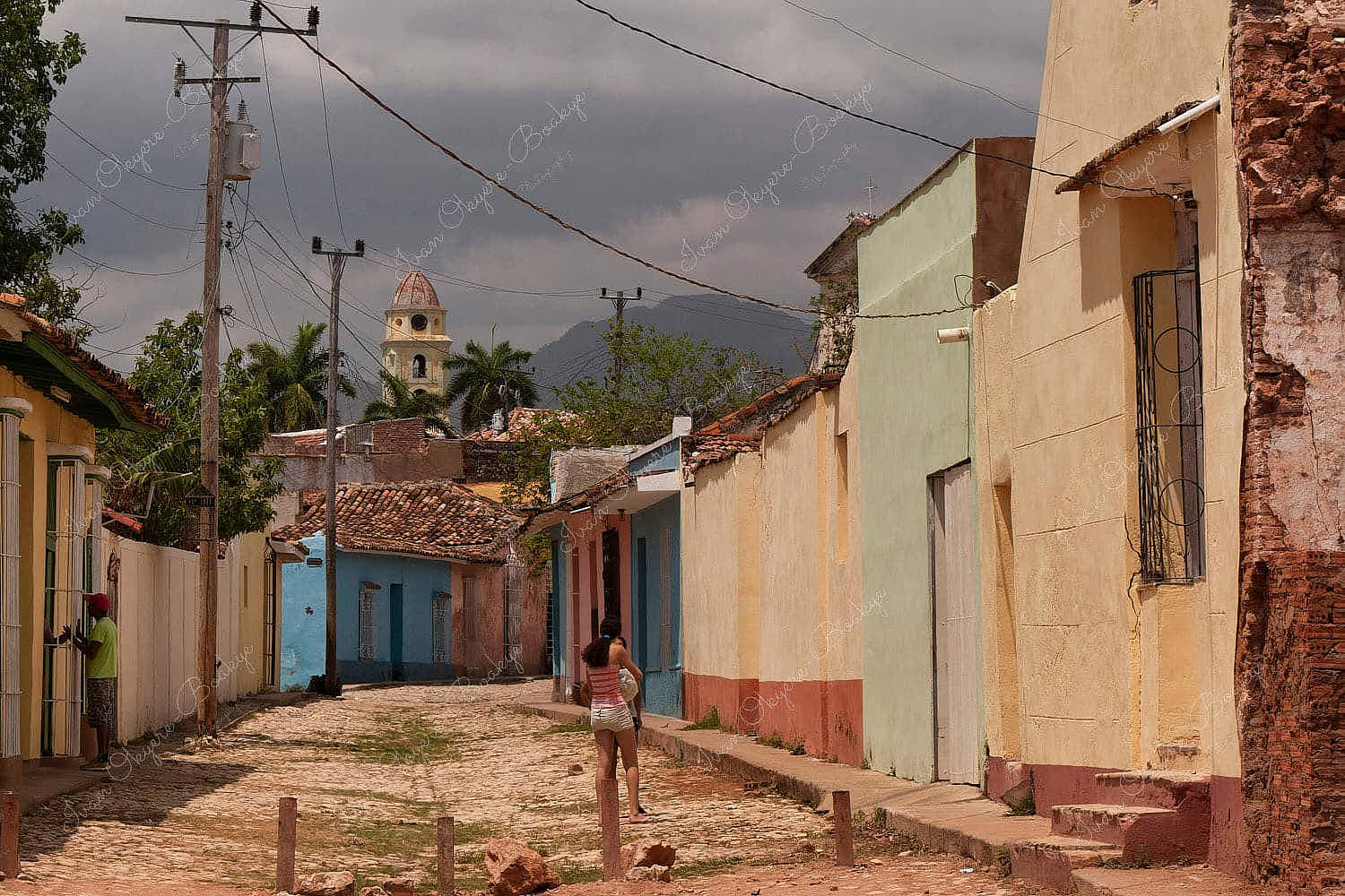 Girl friends talking in the streets with the Museo Nacional de la Lucha contra Bandidos in the background in Trinidad, Cuba