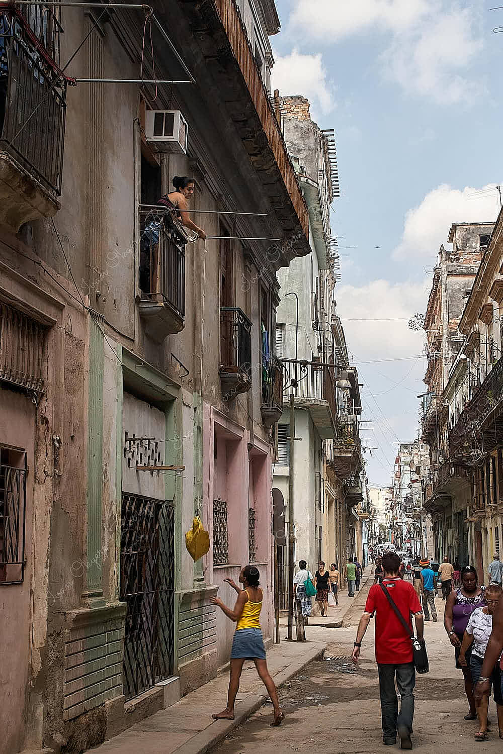 Cuban woman lowering bag of items to woman on street, Habana Vieja; Havana, Cuba