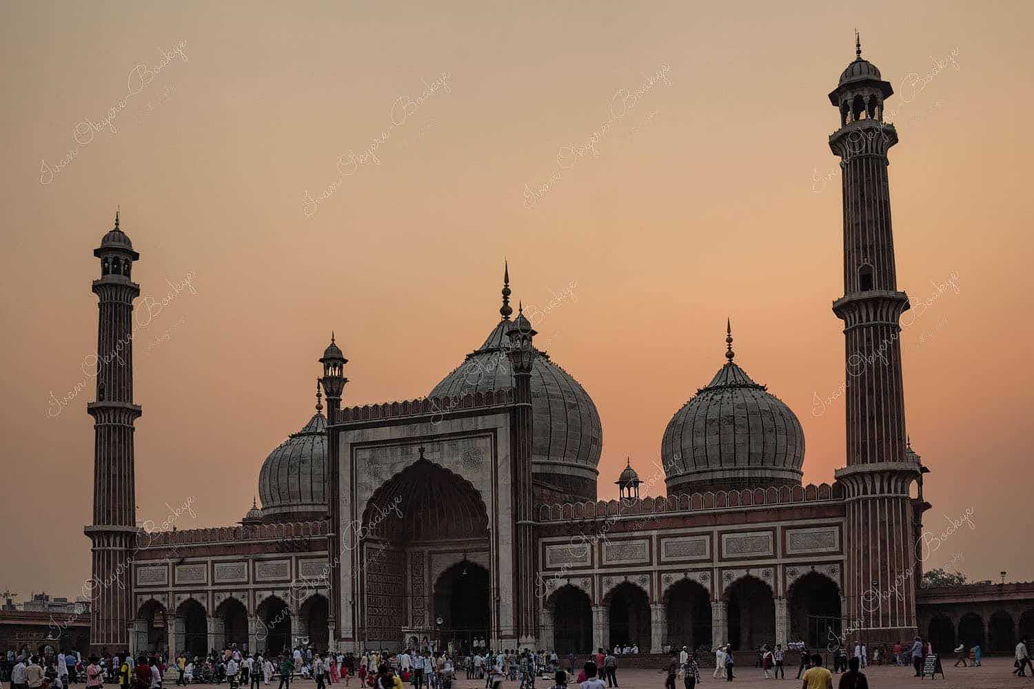 Worshippers outside Jama Masjid Mosque at sunset in Delhi, India