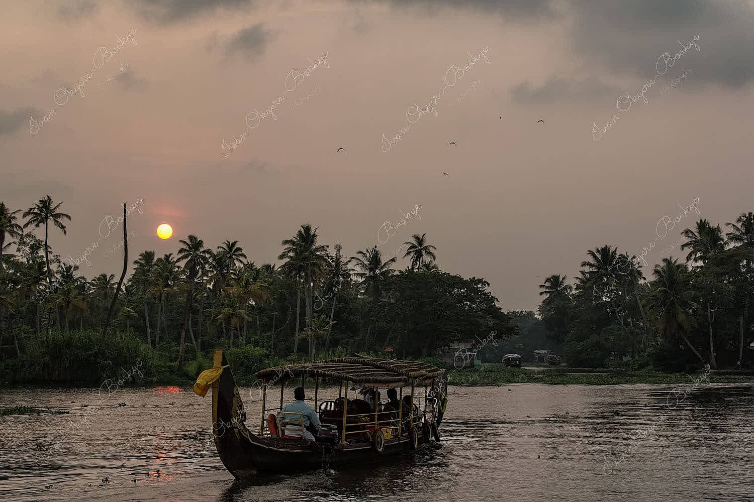 Riverboat carrying passengers on the river in the Alleppey Backwaters at sunset in Kerala, India