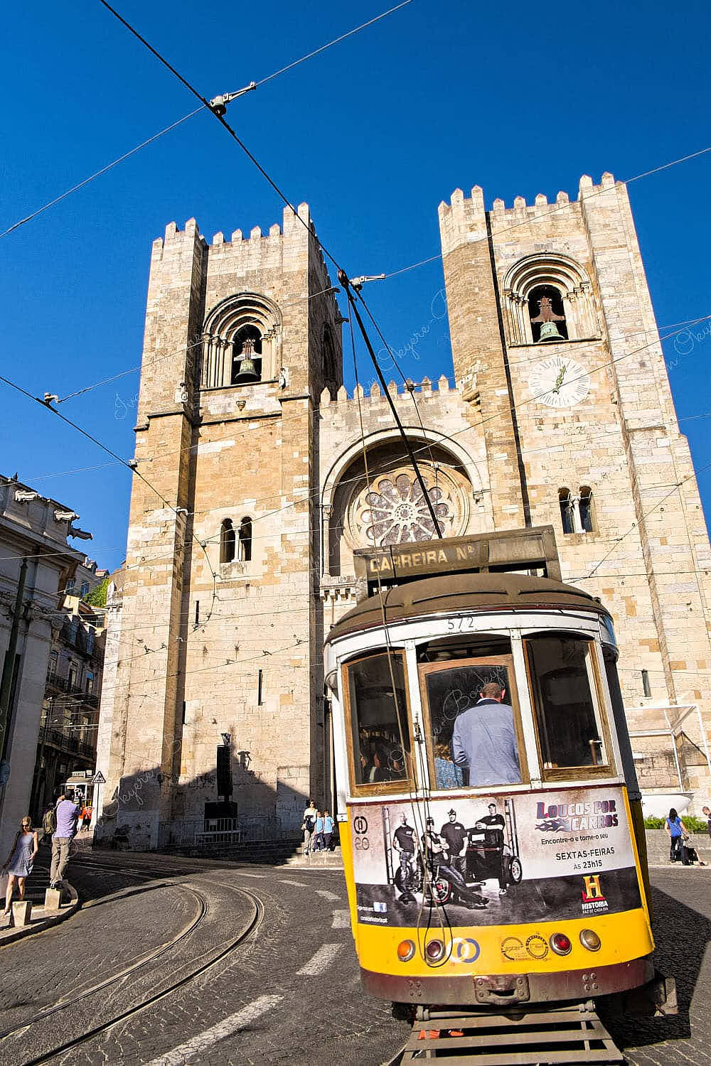 A classic yellow Carreira Tram 28 passing The Lisbon Cathedral, Lisbon, Portugal