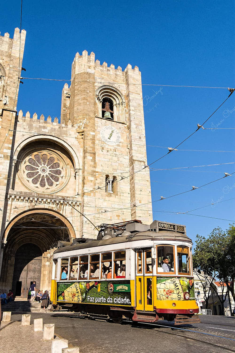 A classic yellow Estrella Tram 28 passing The Lisbon Cathedral, Lisbon, Portugal