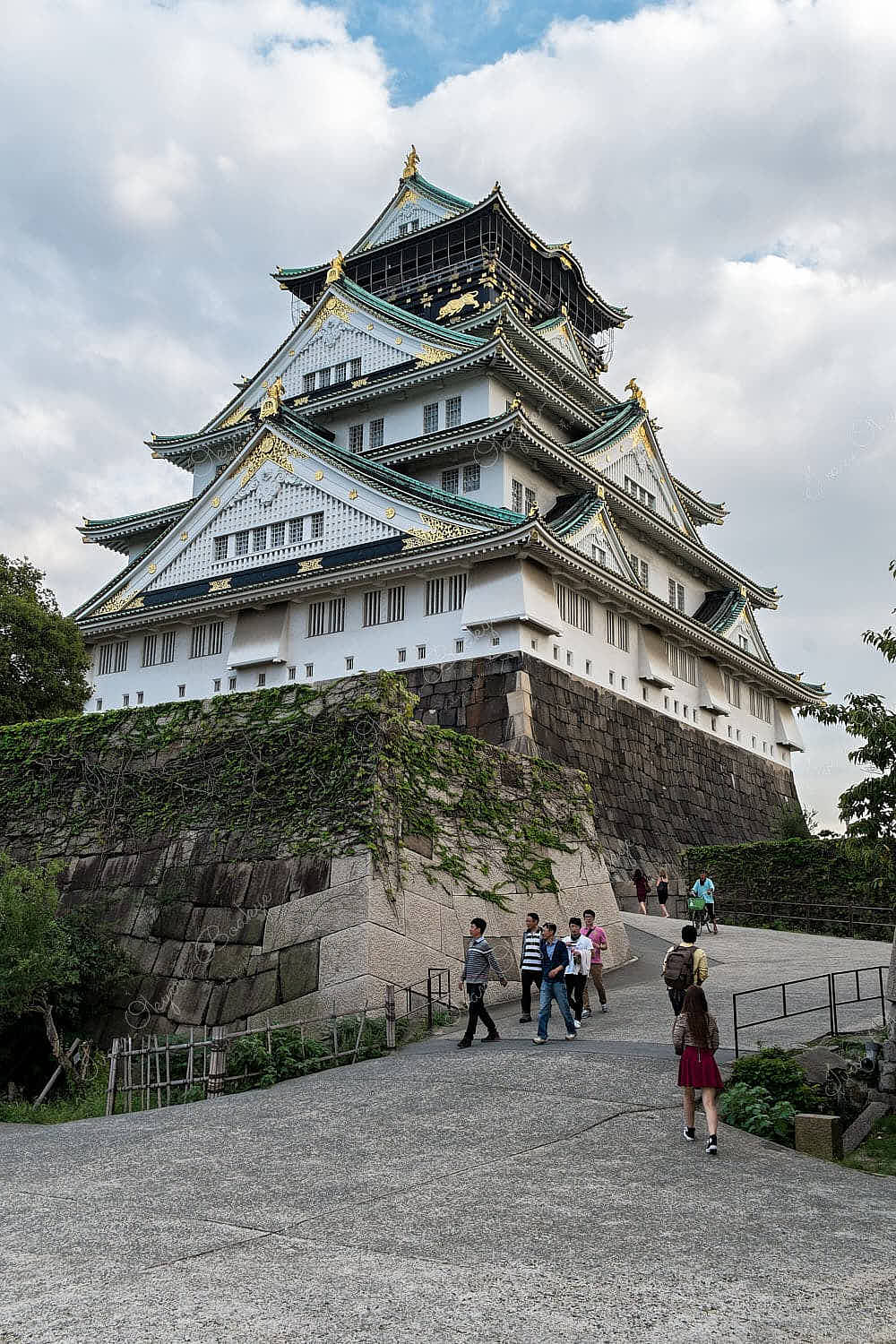 Tourists walking up towards the majestic imposing Osaka Castle (Osakajo) in Osaka, Japan
