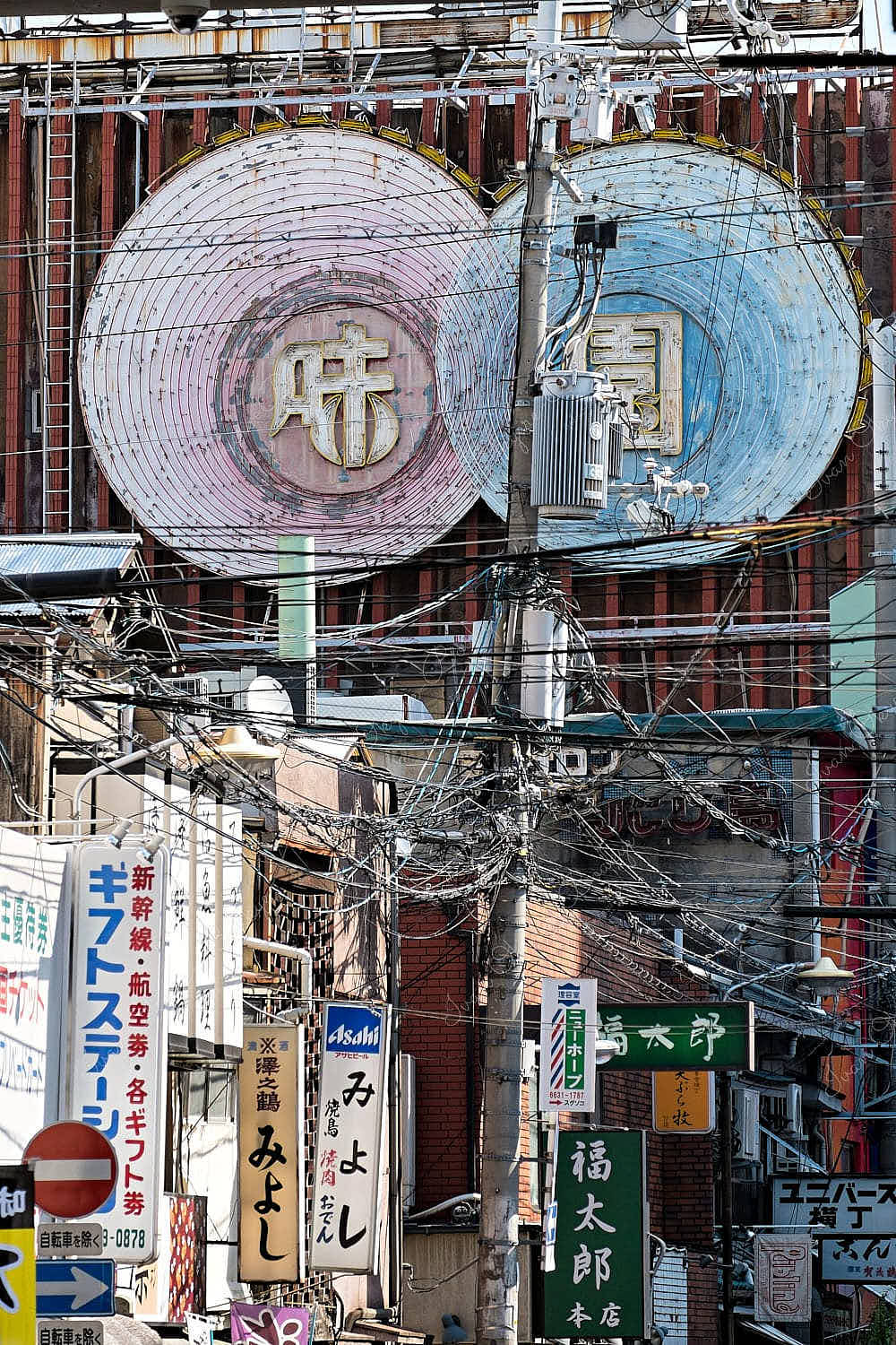 Tangled power lines among multiple advertising signs and boards in an Osaka side street, Japan