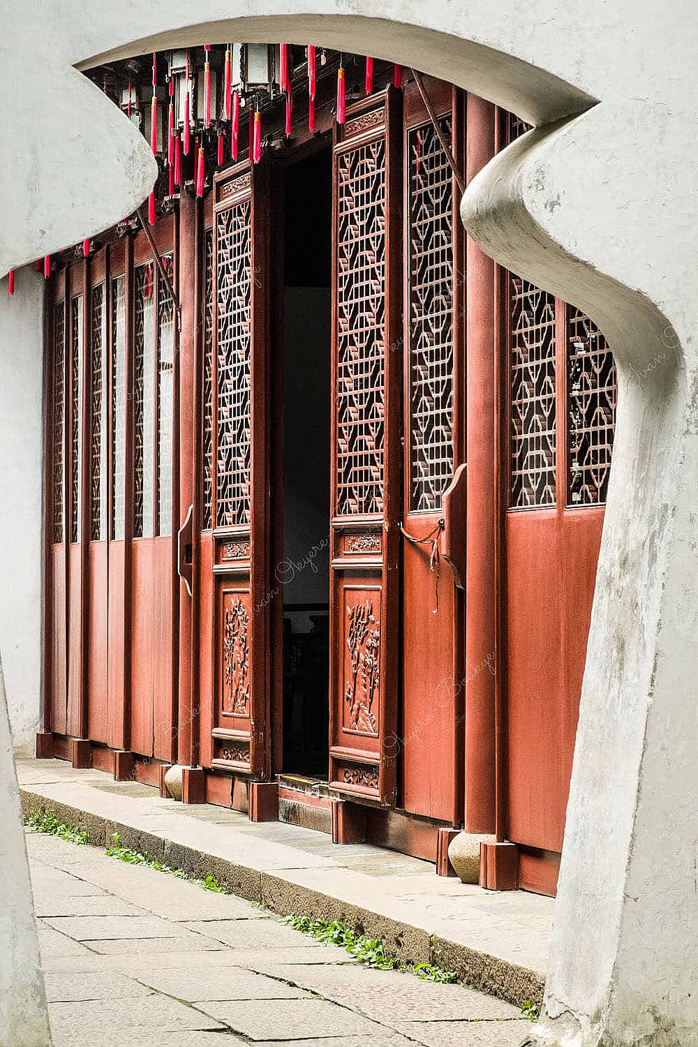 View of elaborate designed traditional Chinese wooden doors through an archway in Yuyuan Garden, Shanghai, China