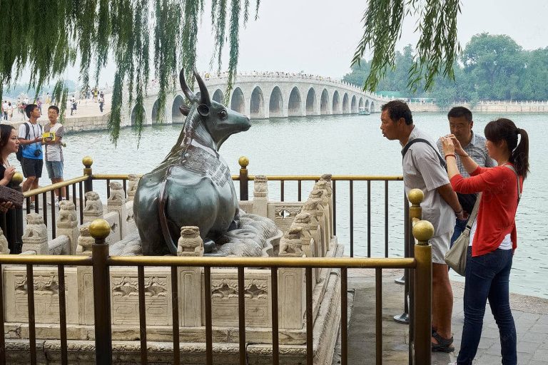 Cow statue and 100 arch bridge in background, Kunming Lake, Beijing, China
