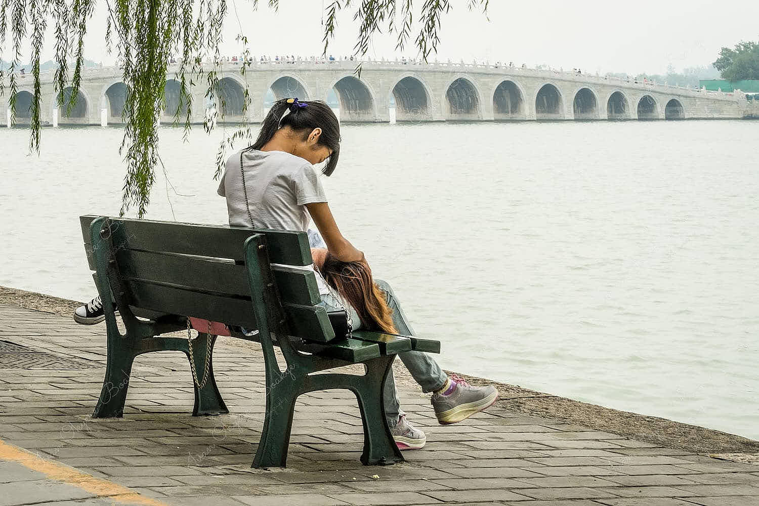 Two girls on a bench with the amazing 17 Arch Bridge in the background at Kunming Lake, Beijing, China