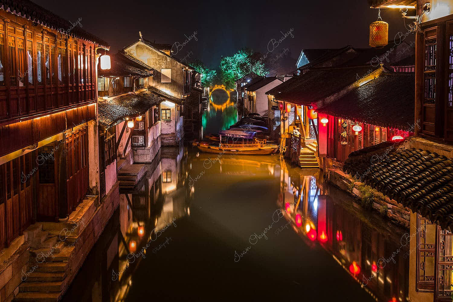 Night time view of illuminated traditional Chinese houses, gondola, canal and stone bridge in the historic Zhouzhuang water town, China