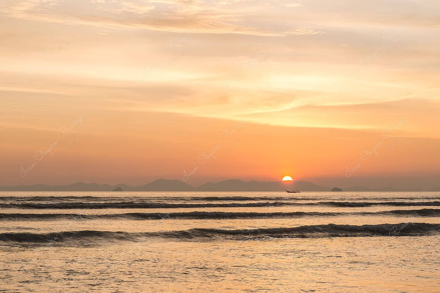Sun setting behind mountain with fishing boat in foreground at Railey Beach, Thailand