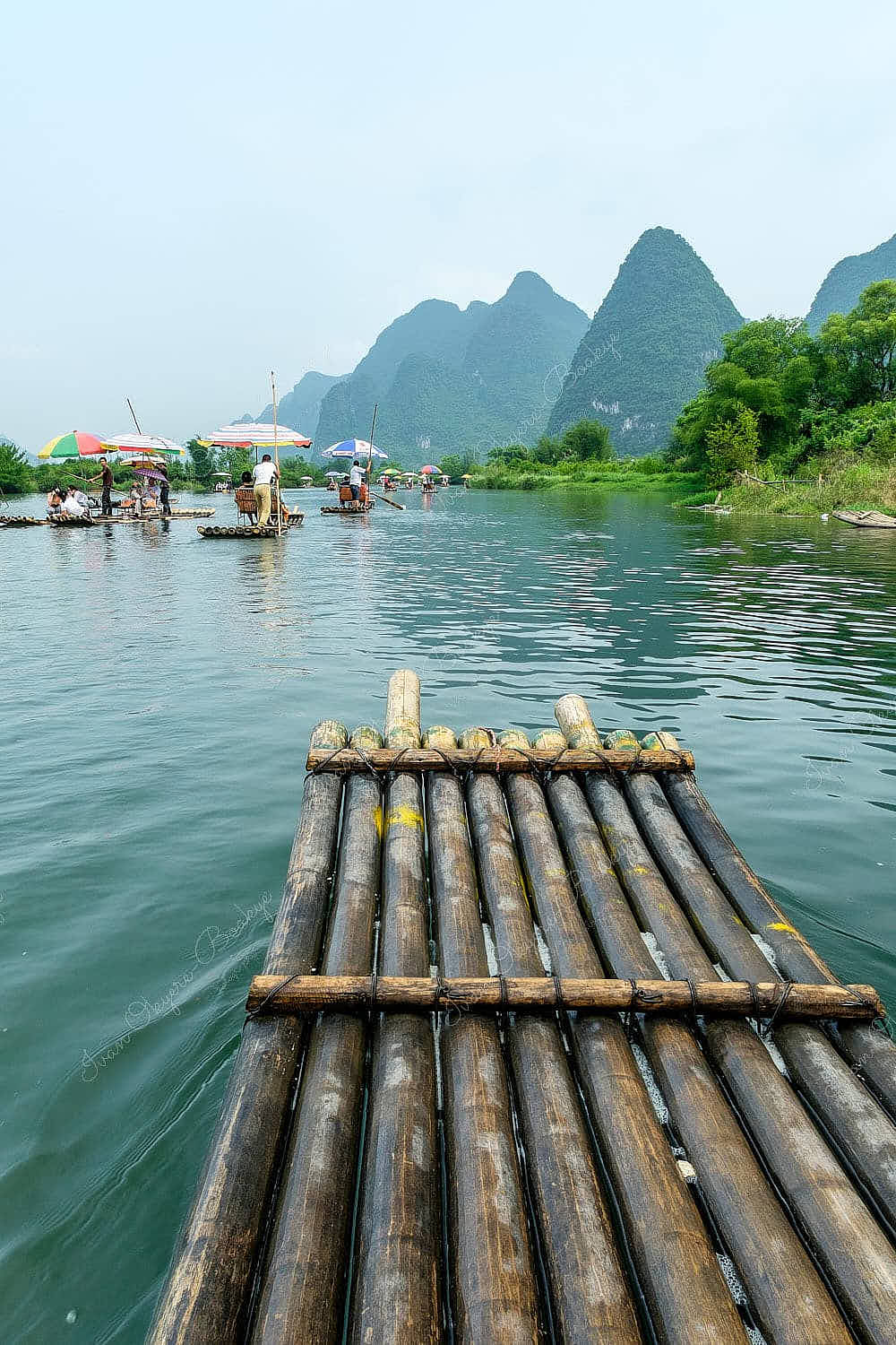 Tourists sailing on bamboo raft on Yulong River surrounded by karst mountains in Guilin, China