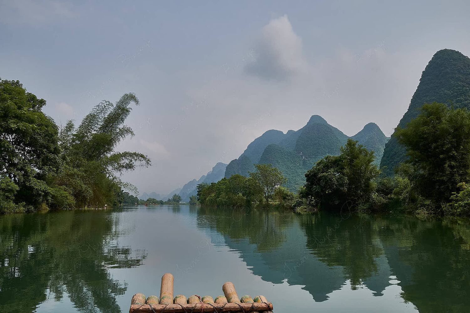 Sailing in bamboo raft on Yulong River surrounded by karst mountains and trees in Guilin, China