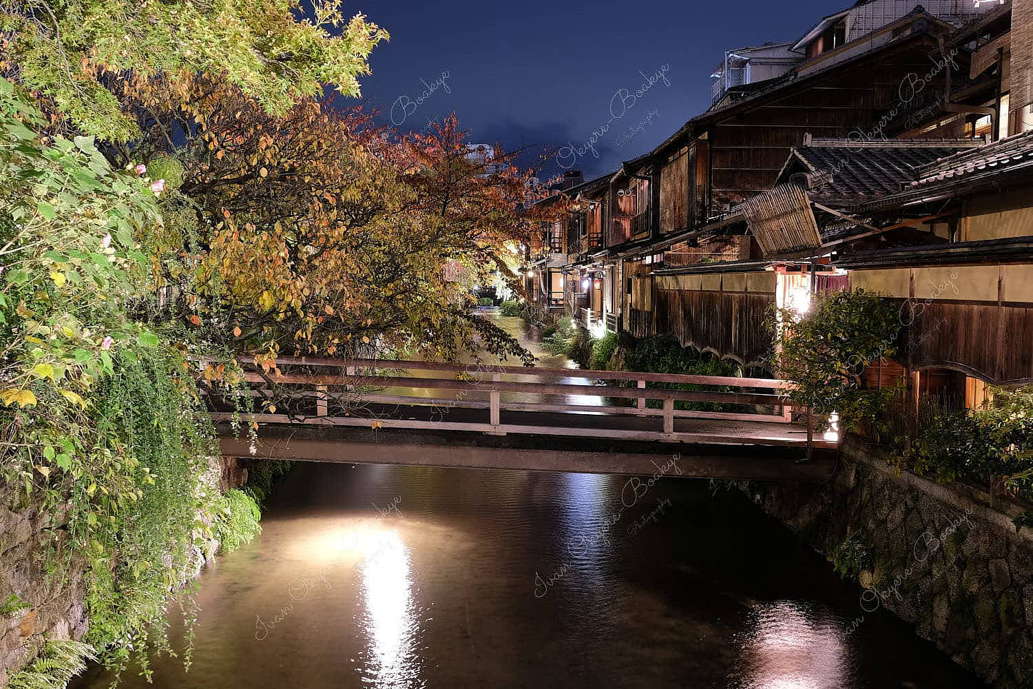 An illuminated wooden bridge leading into traditional wooden Japanese restaurants in Kyoto, Japan