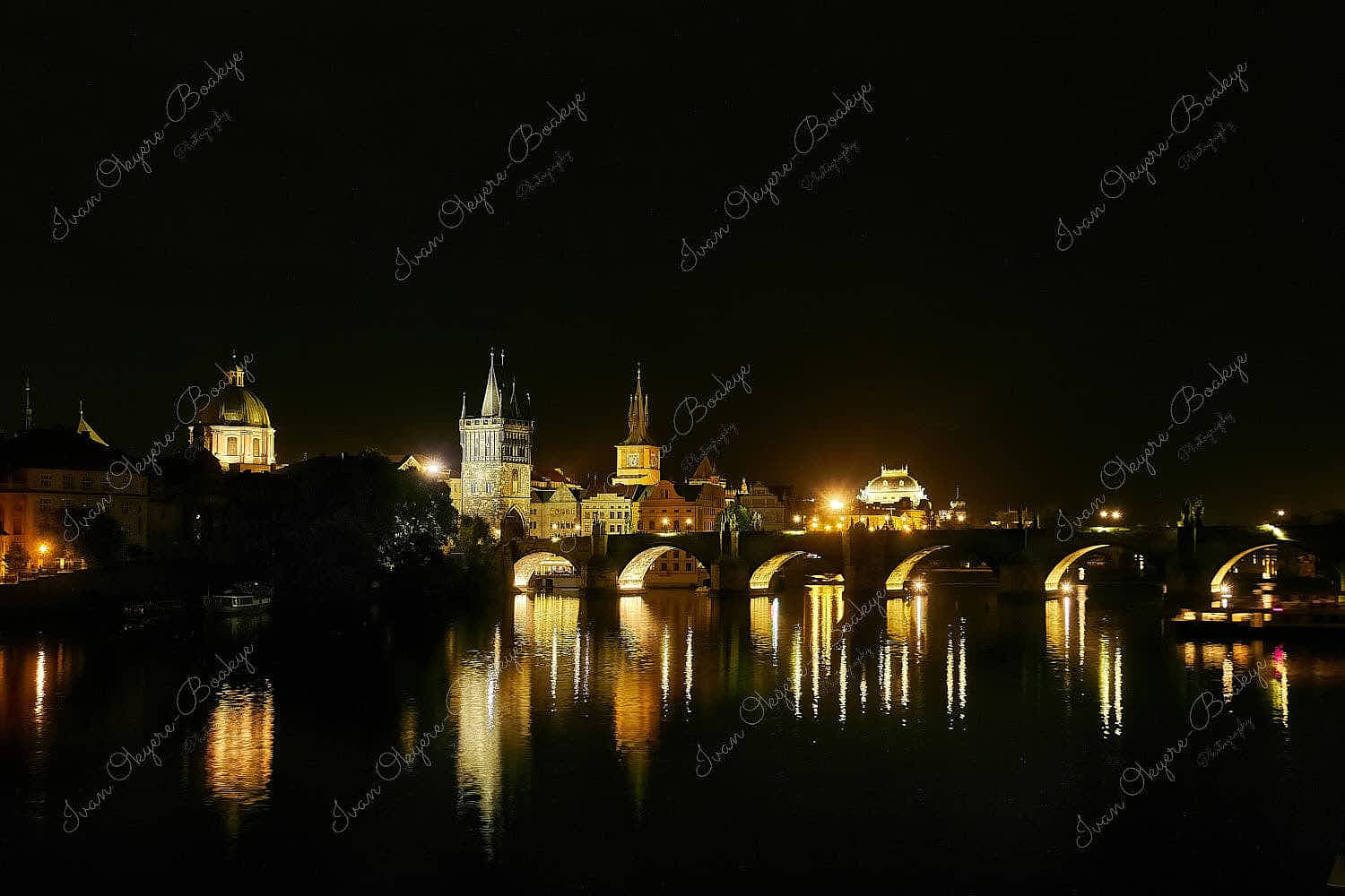 Riverside night time view of the illuminated Charles Bridge, Prague Castle and St. Vitus Cathedral in Prague, Czech Republic