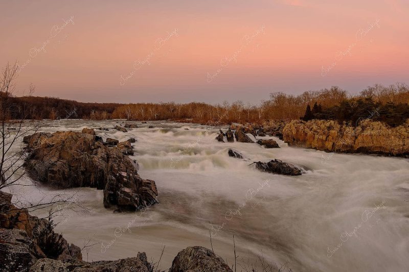 The Potomac River cascading over several boulders at sunset in Great Falls Park, Washington, America