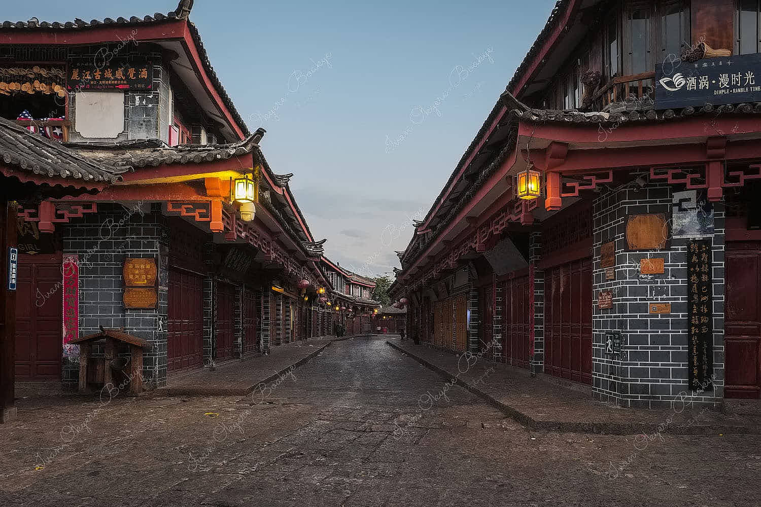 Quiet street with traditional Chinese shops and restaurant and hanging lanterns at dawn in Lijiang, China