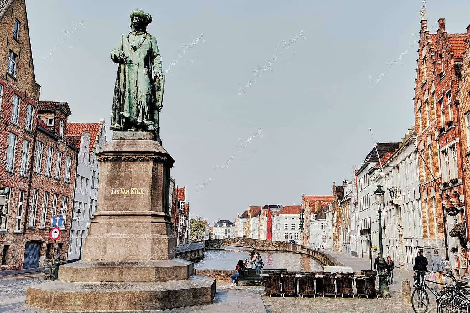 The imposing statue of the famous Belgian master painter Jan Van Eyck in Jan Van Eyckplein surrounded by classic crow-stepped gable styled houses, Bruges, Belgium